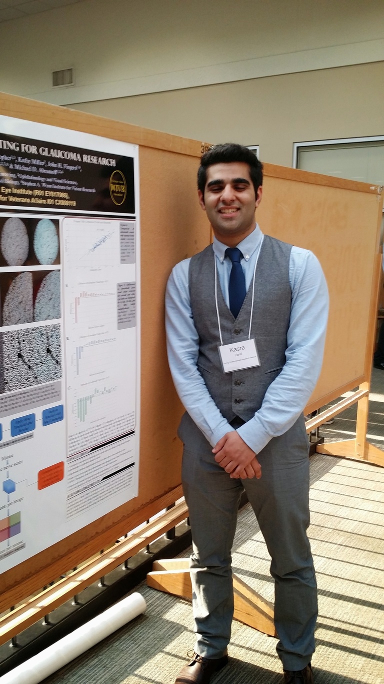 Young man in a tie stands by his research poster