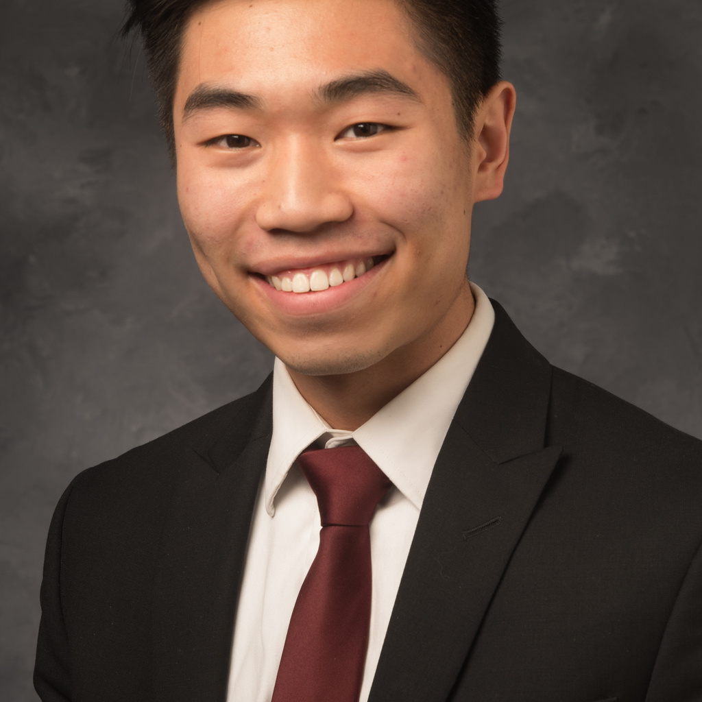 Young Asian man smiling in front of dark gray back drop