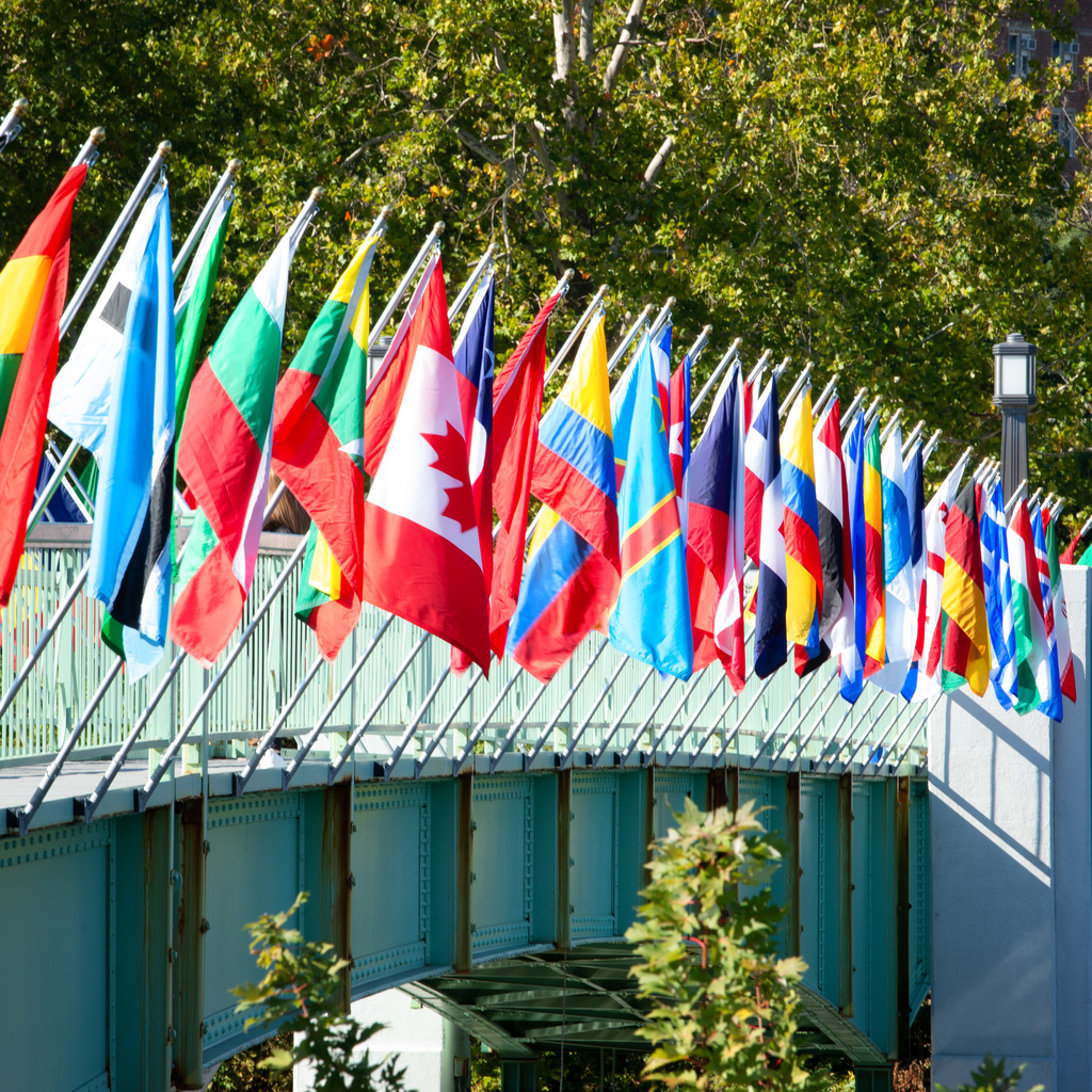 A row of flags on a gray metal bridge