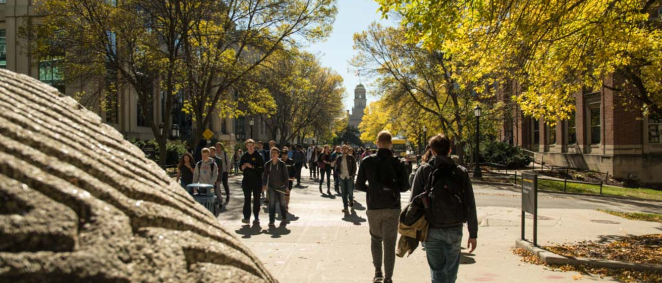 Students walking towards Old Cap on a sunny fall day